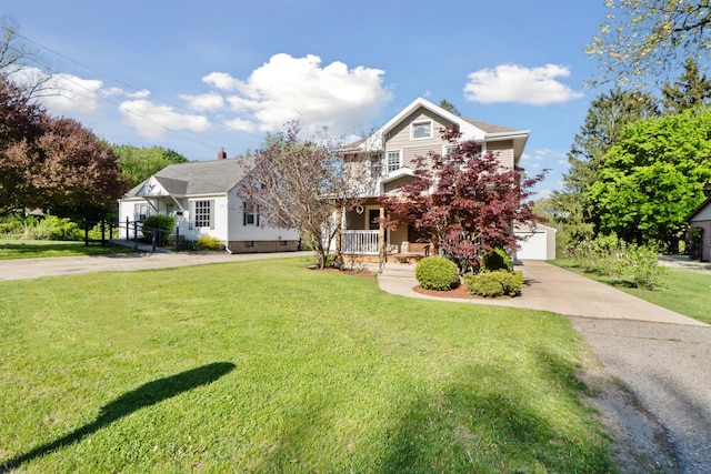 view of front facade with a front yard, covered porch, concrete driveway, and a garage