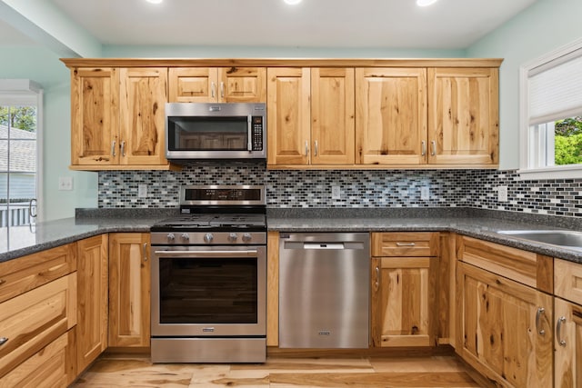 kitchen featuring stainless steel appliances, dark countertops, decorative backsplash, light wood-style floors, and recessed lighting