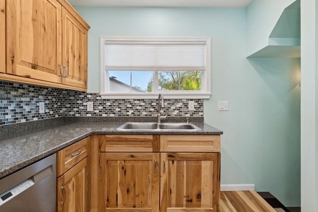 kitchen with a sink, stainless steel dishwasher, dark countertops, and decorative backsplash