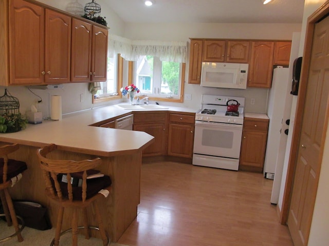 2625 Rolling Ridge Ln NW, Grand Rapids, MI 49534 - kitchen with white appliances, a sink, a peninsula, light wood finished floors, and light countertops