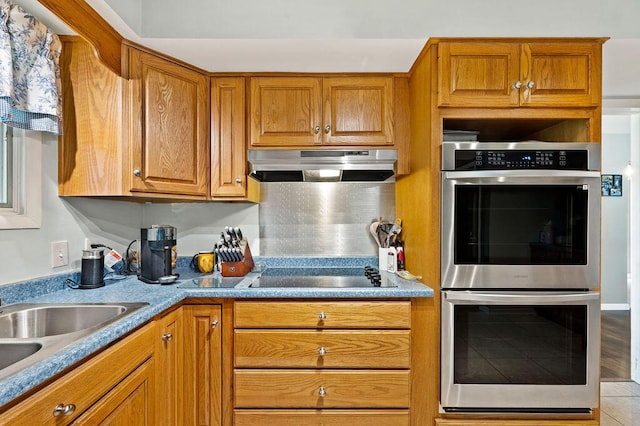 2655 Tanbark Trl, Saint Joseph, MI 49085 - kitchen with double oven, under cabinet range hood, black electric stovetop, a sink, and brown cabinets