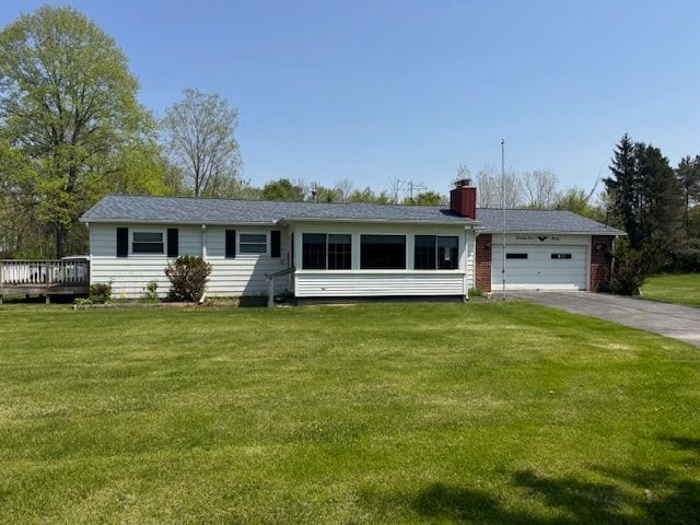 single story home featuring an attached garage, asphalt driveway, a front yard, and a chimney
