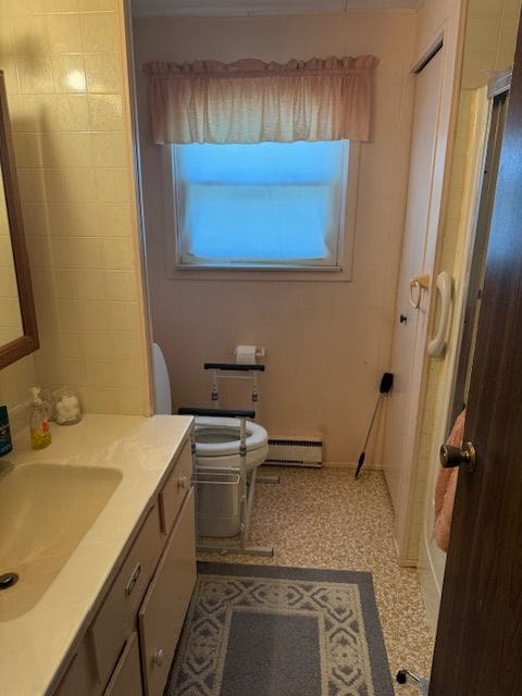 full bath featuring a baseboard heating unit, vanity, toilet, a shower, and baseboards