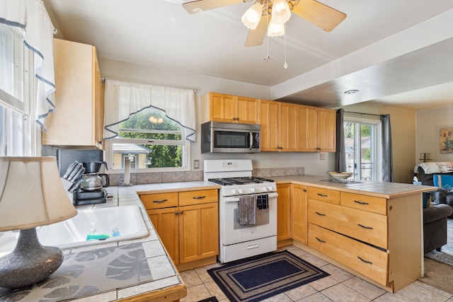 3128 Woodside St, Dearborn, MI 48124 - kitchen featuring stainless steel microwave, gas range gas stove, a peninsula, and light tile patterned floors