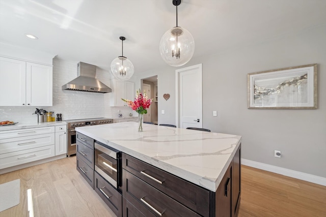 1663 Fairway Dr, Birmingham, MI 48009 - kitchen with wall chimney exhaust hood, appliances with stainless steel finishes, white cabinetry, light wood-type flooring, and decorative backsplash