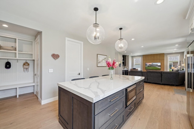 1663 Fairway Dr, Birmingham, MI 48009 - kitchen with light wood-type flooring, stainless steel microwave, hanging light fixtures, a kitchen island, and light stone counters