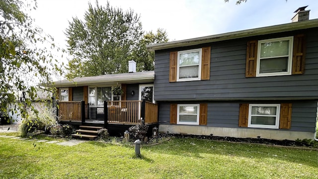 split level home with a chimney, a front yard, and a wooden deck