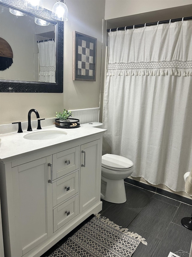 bathroom with toilet, wainscoting, and vanity