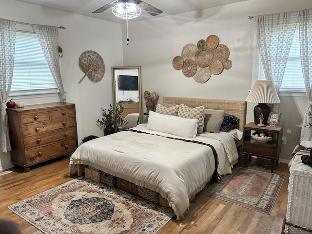 bedroom with wood finished floors, multiple windows, and a ceiling fan