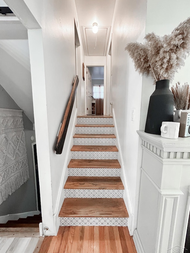stairs featuring attic access and wood finished floors