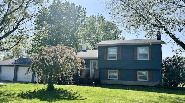 split level home with a chimney, a front yard, driveway, and an attached garage