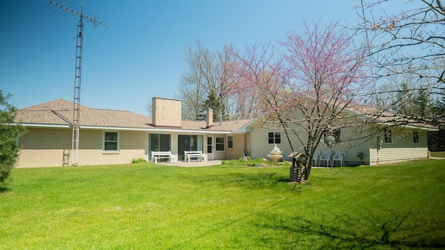 7198 Farr Rd, Onekama, MI 49675 - rear view of house with a chimney, a lawn, a sunroom, and brick siding