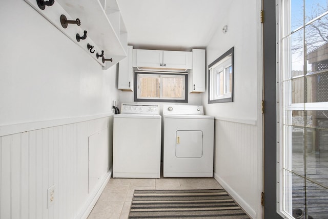 clothes washing area featuring cabinet space, washer and dryer, light tile patterned floors, and a wainscoted wall
