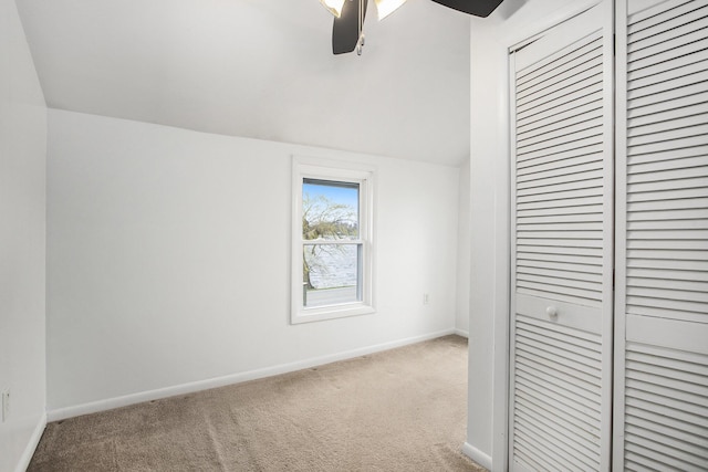 unfurnished bedroom with carpet flooring, baseboards, a closet, vaulted ceiling, and ceiling fan