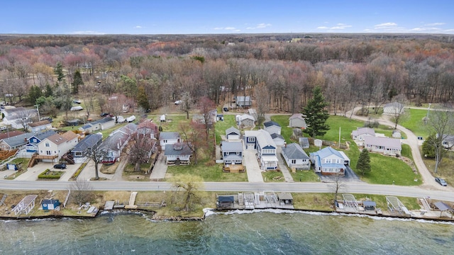 view of property location with a heavily wooded area, nearby suburban area, and a large body of water