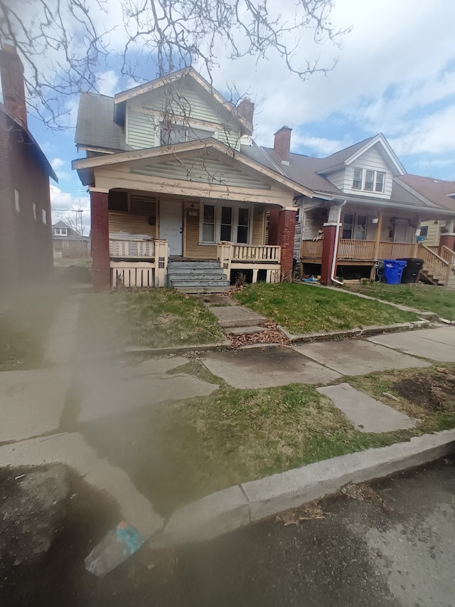 9591 American St, Detroit, MI 48204 - view of front facade featuring a porch, a chimney, and a front yard