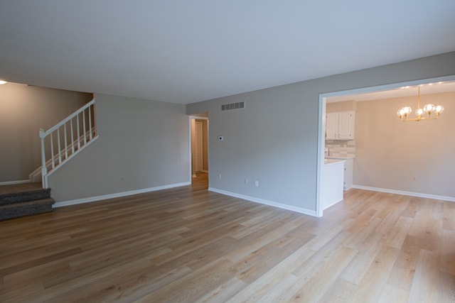 37374 Stonegate Cir, Clinton Township, MI 48036 - unfurnished living room with stairs, light wood-type flooring, a chandelier, and baseboards