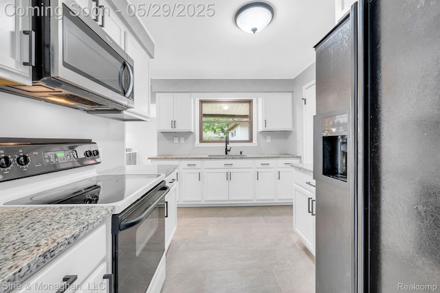 2514 Hearthside Dr, Ypsilanti, MI 48198 - kitchen with black fridge with ice dispenser, range with electric cooktop, stainless steel microwave, a sink, and white cabinetry