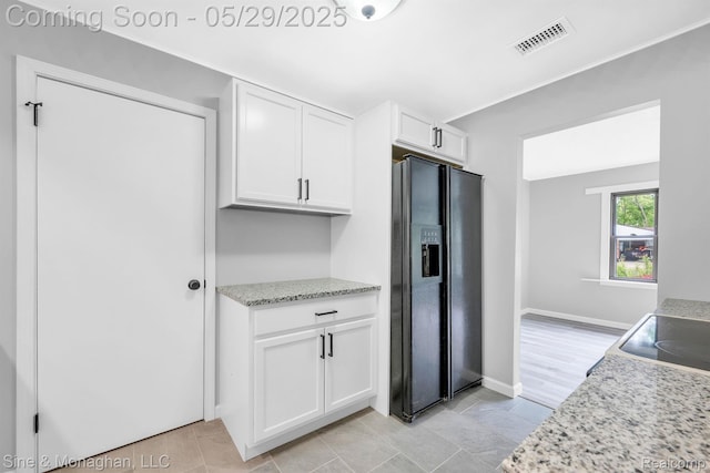 2514 Hearthside Dr, Ypsilanti, MI 48198 - kitchen featuring black fridge with ice dispenser, white cabinets, baseboards, and light stone countertops