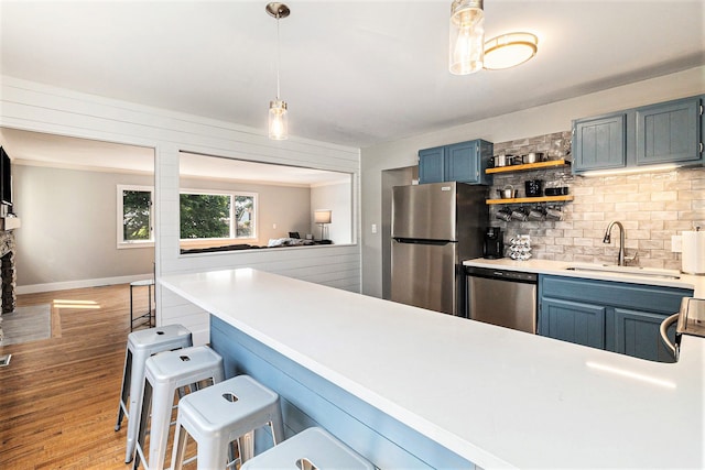 926 Brighton Lake Rd, Brighton, MI 48116 - kitchen featuring stainless steel appliances, a sink, decorative backsplash, a breakfast bar area, and blue cabinets