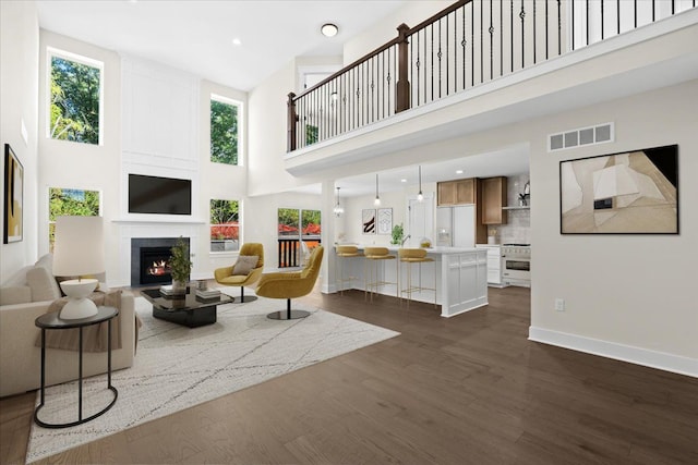 2080 Crested Butte Dr, White Lake, MI 48383 - living area featuring a towering ceiling, dark wood-style flooring, a lit fireplace, baseboards, and recessed lighting