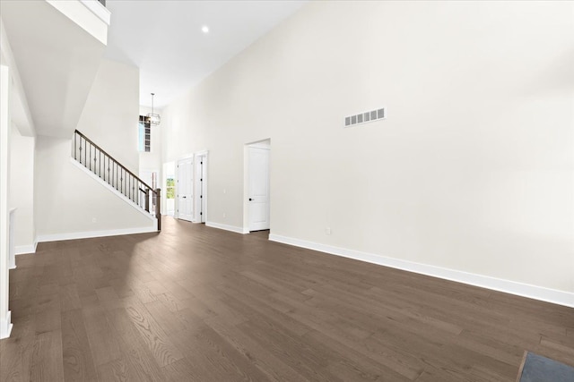 2080 Crested Butte Dr, White Lake, MI 48383 - unfurnished living room featuring a high ceiling, baseboards, stairway, and dark wood finished floors
