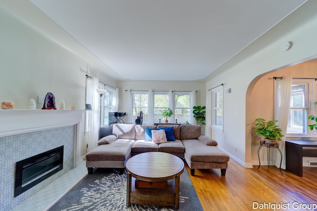 1573 N Whitehall Rd, Muskegon, MI 49445 - living room with wood finished floors, arched walkways, a tile fireplace, and baseboards