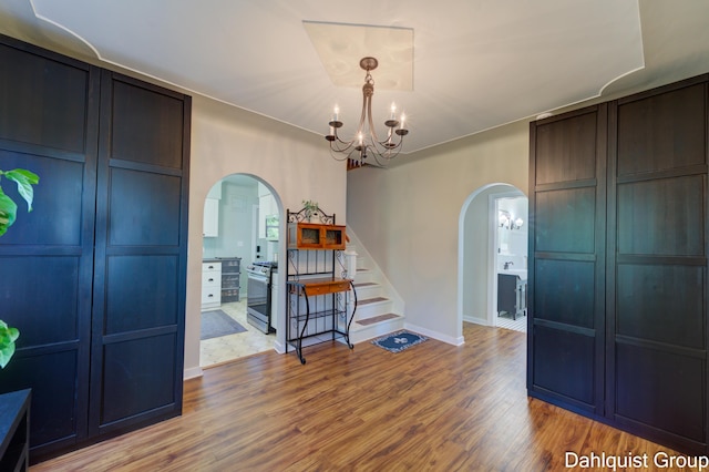1573 N Whitehall Rd, Muskegon, MI 49445 - dining space with arched walkways, a chandelier, wood finished floors, stairs, and baseboards