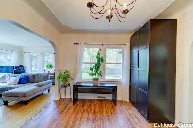 1573 N Whitehall Rd, Muskegon, MI 49445 - living area featuring arched walkways, light wood finished floors, a chandelier, and baseboards
