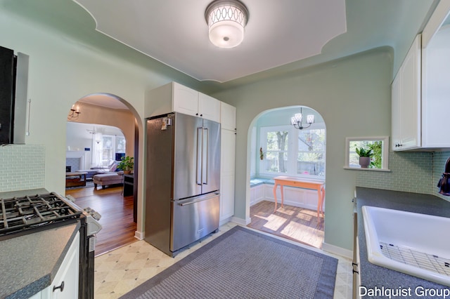 1573 N Whitehall Rd, Muskegon, MI 49445 - kitchen with high quality fridge, gas range oven, dark countertops, arched walkways, and white cabinetry