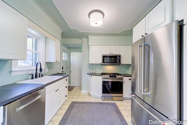 1573 N Whitehall Rd, Muskegon, MI 49445 - kitchen featuring appliances with stainless steel finishes, a sink, white cabinets, tasteful backsplash, and dark countertops