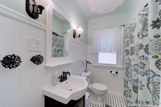 1573 N Whitehall Rd, Muskegon, MI 49445 - full bath with toilet, vanity, a decorative wall, tile patterned floors, and a wainscoted wall