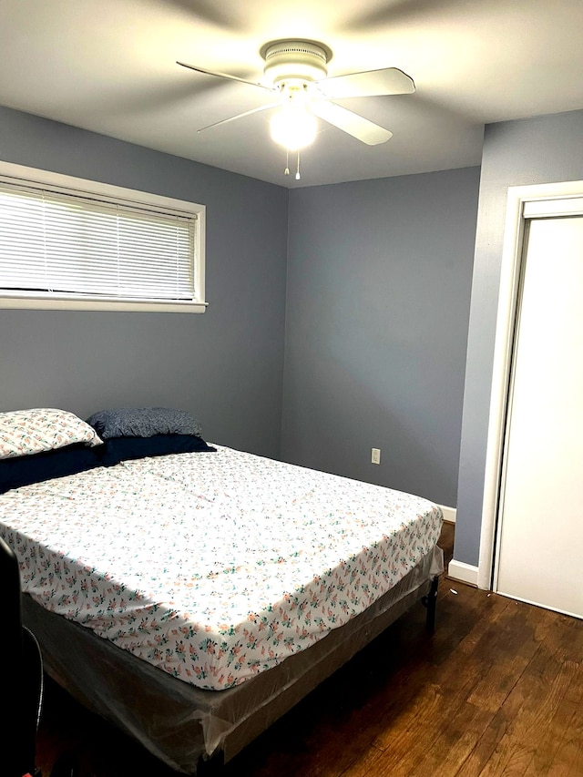 bedroom featuring wood finished floors, a ceiling fan, and baseboards