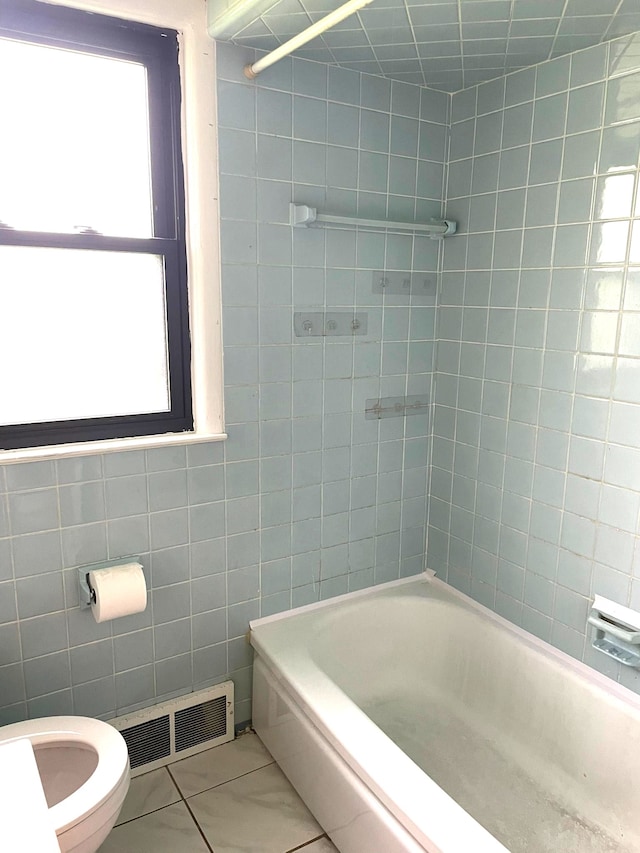 full bath with toilet, tile walls, tile patterned floors, and bathtub / shower combination