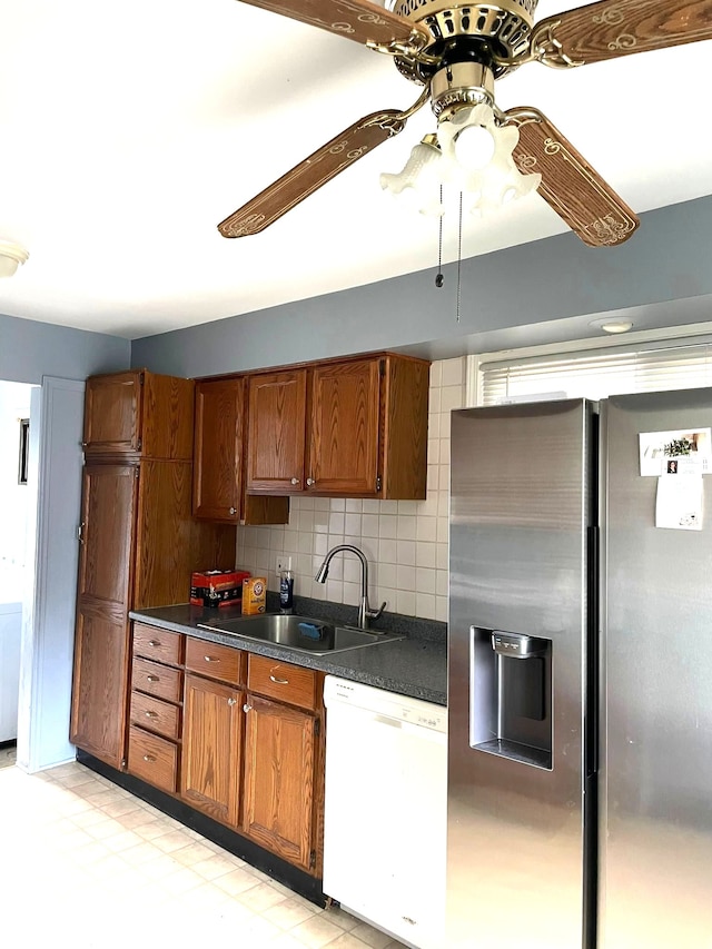 kitchen with stainless steel fridge, dishwasher, dark countertops, a ceiling fan, and brown cabinets