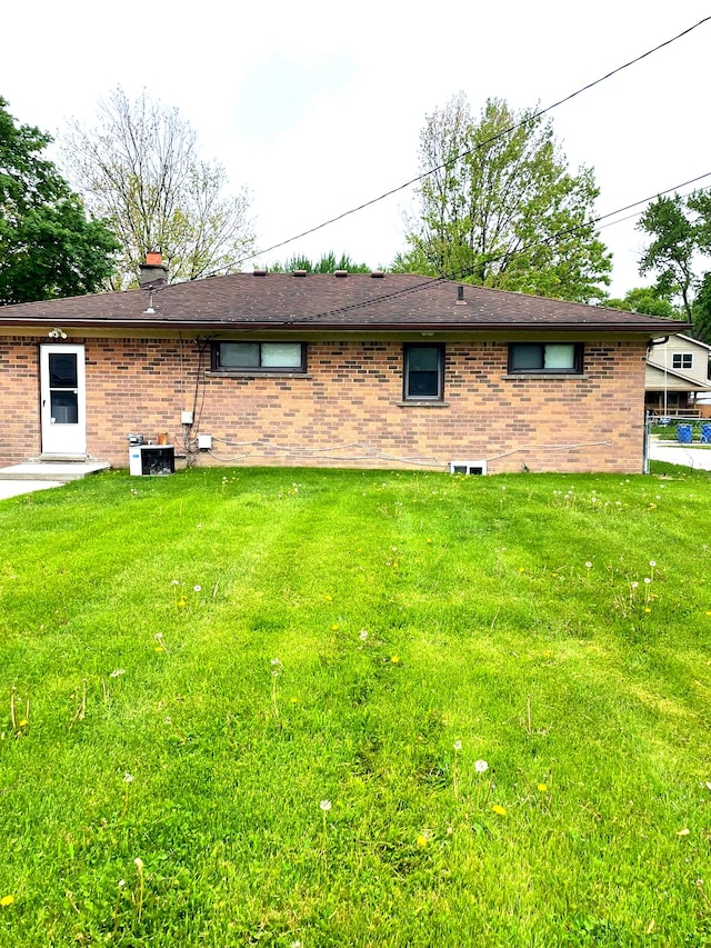 back of property featuring brick siding and a lawn