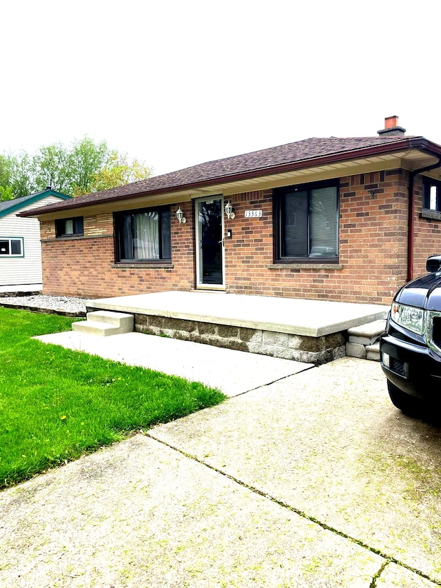 single story home with brick siding and a chimney