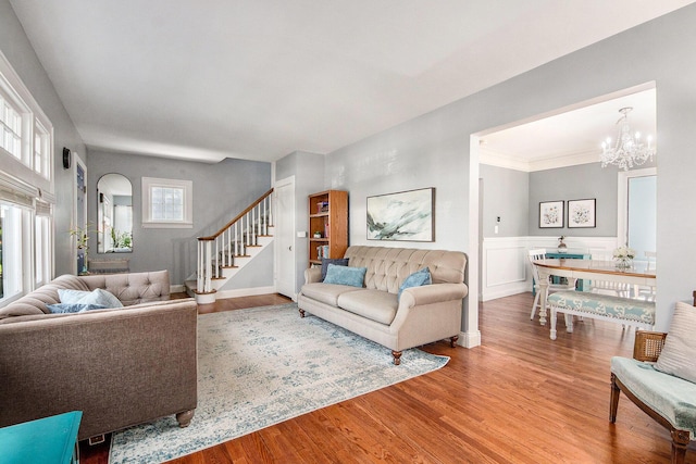 living room featuring wood finished floors, stairway, a chandelier, and wainscoting