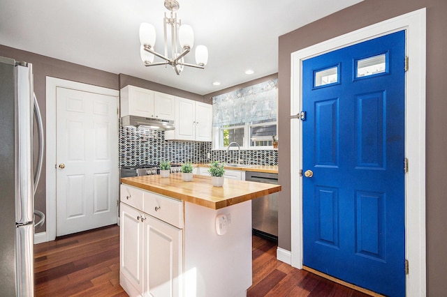 kitchen featuring wood counters, stainless steel appliances, under cabinet range hood, backsplash, and dark wood-style flooring