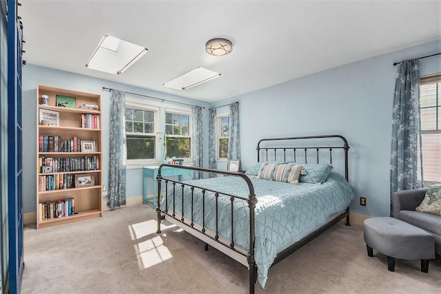 carpeted bedroom featuring a skylight and baseboards
