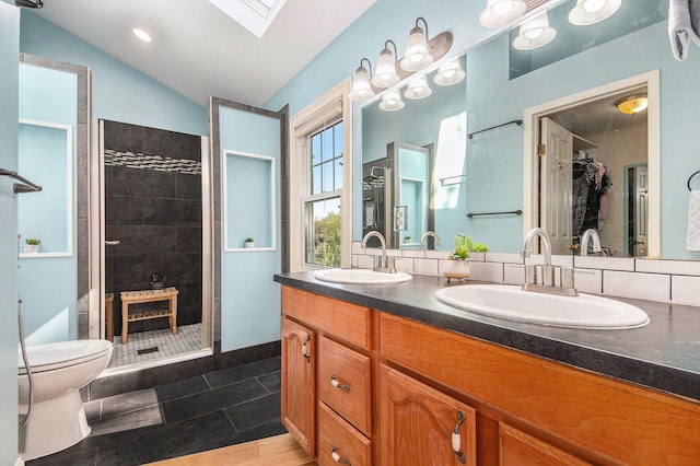 bathroom with tiled shower, a skylight, double vanity, toilet, and vaulted ceiling
