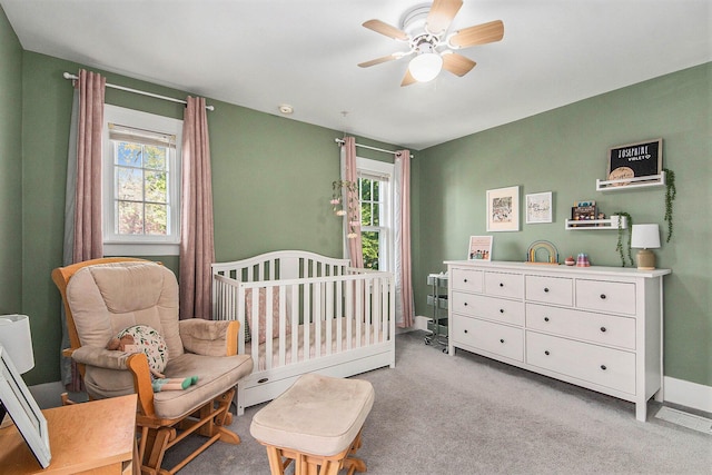 bedroom with multiple windows, a nursery area, light colored carpet, and baseboards