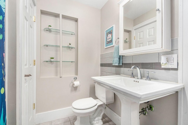 bathroom featuring toilet, tile patterned floors, baseboards, and a sink