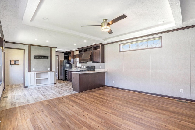 6922 Knotty Pine St NE, Rockford, MI 49341 - kitchen featuring a tray ceiling, light wood-style flooring, a peninsula, dark brown cabinets, and a ceiling fan