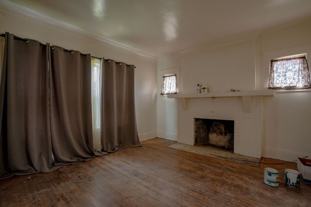 unfurnished living room with ornamental molding, a fireplace, wood finished floors, plenty of natural light, and baseboards