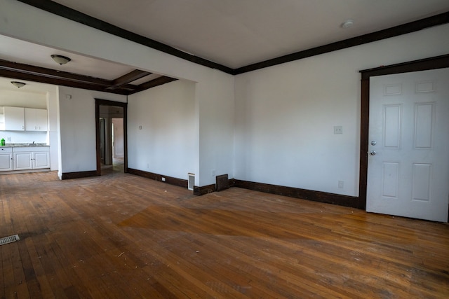 unfurnished room featuring dark wood-type flooring, baseboards, and beam ceiling