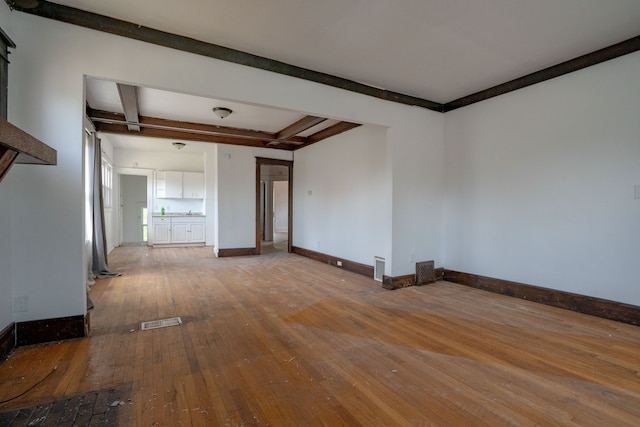 empty room with hardwood / wood-style flooring, beamed ceiling, and baseboards