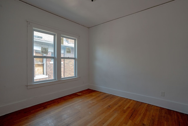spare room featuring baseboards and light wood finished floors