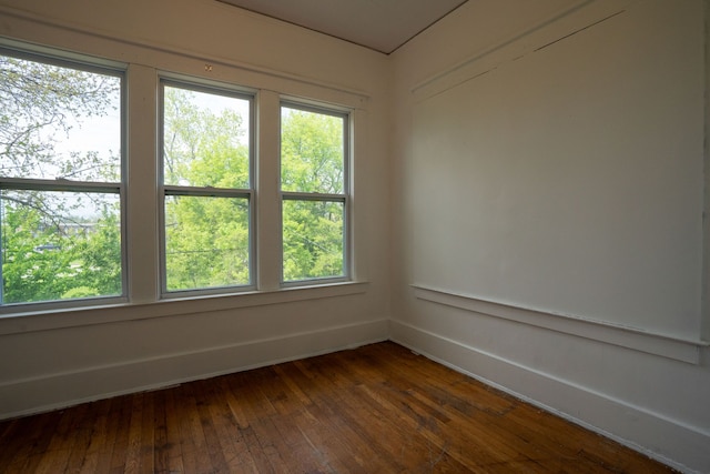 empty room featuring baseboards and dark wood-type flooring
