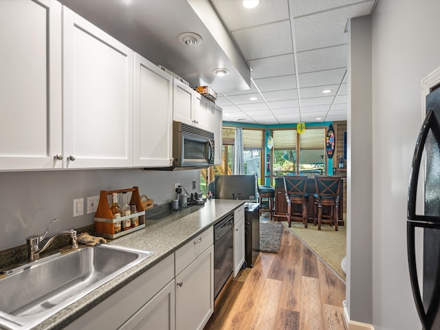 3097 Lansdowne Rd, Waterford, MI 48329 - kitchen with a sink, black appliances, light wood finished floors, white cabinets, and recessed lighting